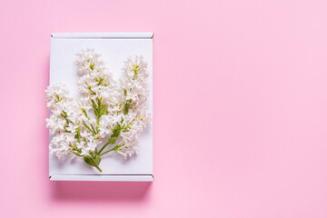 One gift boxes decorated with lilac flowers on pink background, copy space