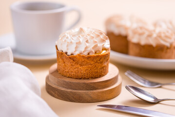 Sweet tart with cream and cup of coffee on beige table