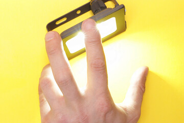 Luminous diode floodlight that holds a male hand. Lighting device. Modern energy-saving...