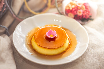 Homemade caramel custard pudding on white plate with brown fabric