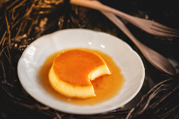 Homemade caramel custard pudding on white plate with wood background