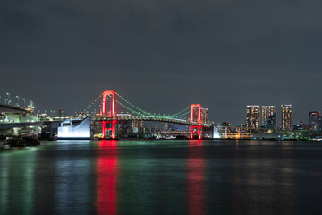 Fototapeta na wymiar Nightview of Rainbow Bridge, illuminated in red as a sign of coronavirus alert.