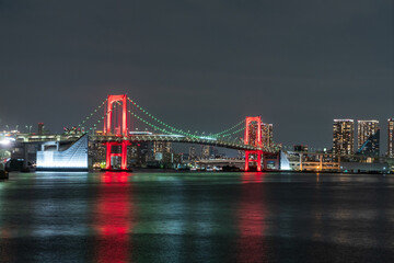 Nightview of Rainbow Bridge, illuminated in red as a sign of coronavirus alert.