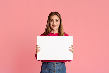 Happy smiling teenage girl holding white sheet of paper in hands with empty space
