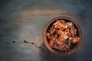 Char Grilled Chicken Wings in the plate on the old table background.