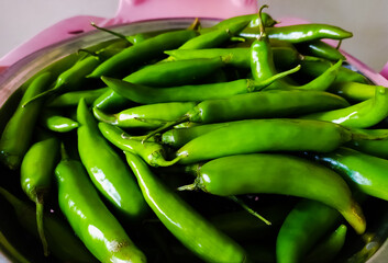 fresh green serrano peppers in a bowl, closeup