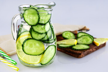 Cold drink made of cucumber and lemons, homemade lemonade in a decanter on a white background, shallow depth of field, selective focus. Healthy drinks concept