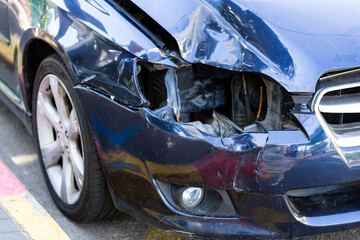 Car crash or accident. Front fender from a blue car and light damage and scratchs on bumper. Broken vehicle detail or close up.
