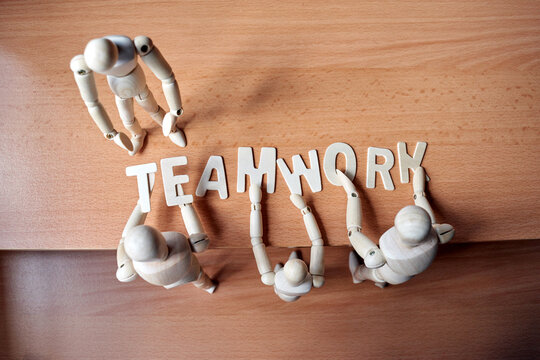 Group of wooden mannequin forming the text TEAMWORK alphabet on table 