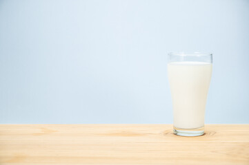 Glass of milk on wooden table and blue background