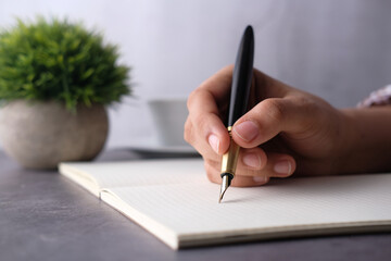 Close up of women hand with pen writing on a diary