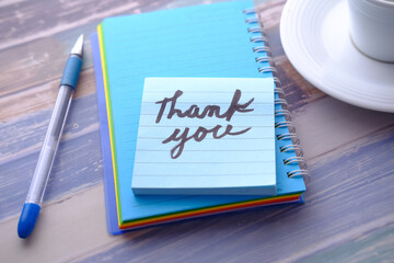 Blue sticky note with thank you on wooden table 