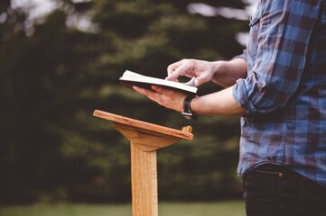 Shallow focus shot of a male near a speech stand with an opened book