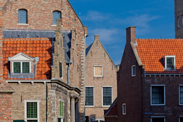 Typical medieval brick facades with Dutch orange roof tiles against a blue sky on a sunny day