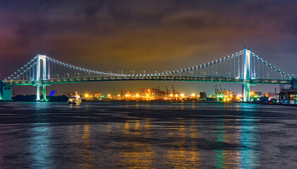 Fototapeta premium Rainbow Bridge colorfully illuminated at night, spanning across Tokyo Bay in Tokyo Japan