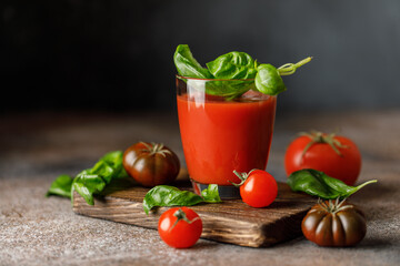 Tomato juice and fresh tomato with basil on rustic background