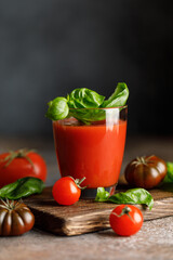 Tomato juice and fresh tomato with basil on rustic background