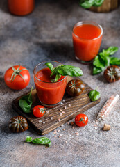 Tomato juice and fresh tomato with basil on rustic background