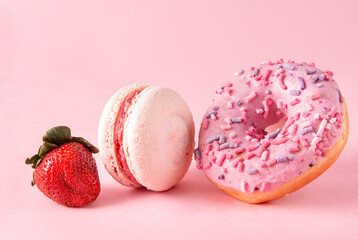 pink donut, macaroon, fresh strawberries on a pink background