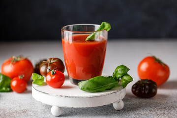 Tomato juice and fresh tomato with basil on rustic background