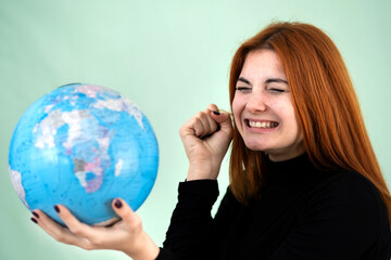 Portrait of a sad worried young woman holding geographic globe of the world in her hands. Travel destination and planet protection concept.
