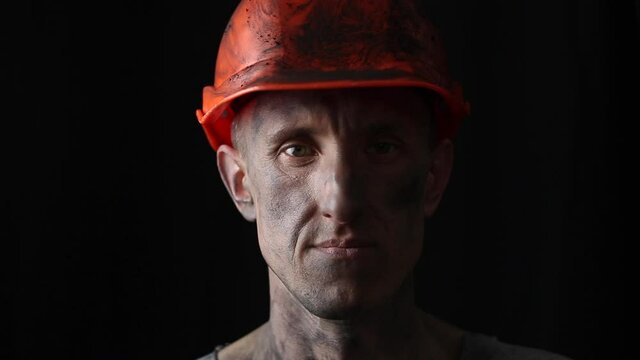 Portrait of a male miner in a helmet on a black background.