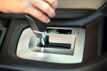 Close up of woman driver holding her hand on automatic gear shift stick driving as car.