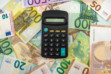 the calculator lies on different euro banknotes. Financial concept. View from above.