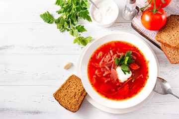 Ukrainian soup with bread, tomato, borscht with sour cream and parsley in a white plate  top view