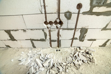Deep grooves and holes in white brick wall made for installation of electrical cables.