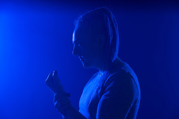 Portrait of a man in with an unusual haircut mohawk iboxing in blue darkness background