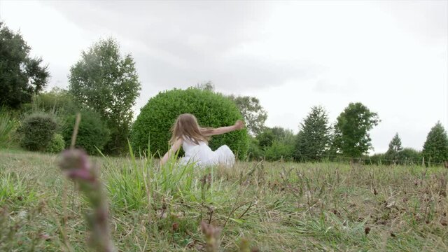 WS TS Girl (6-7) doing cartwheels in meadow / Dinton, Wiltshire, United Kingdom
