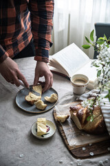 Time for relax. Man hands spreading butter on slice of homemade braided bread (challah) on plate. 