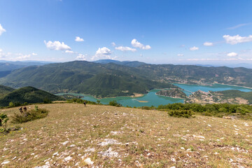 Fototapeta na wymiar Man looking a valley with lake during trekking on mountain. Hiking italian mountain, local tourism and natural landscape. Eco Friendly tourism