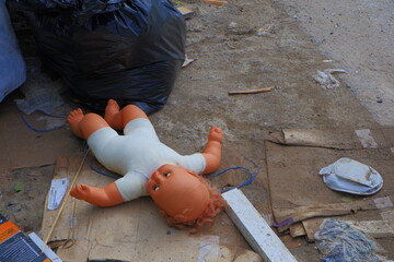a discarded doll among garbage bags