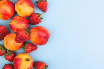 Peaches and strawberries on a blue background. Copyspace.
