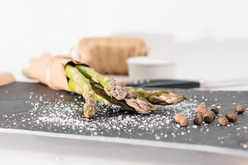 Close-up of organic fresh green asparagus with salt and pepper. Concept of  healthy vegetarian food, diet and home cooking. Copy space.