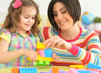 Close up portrait of young mother playing with little daughter