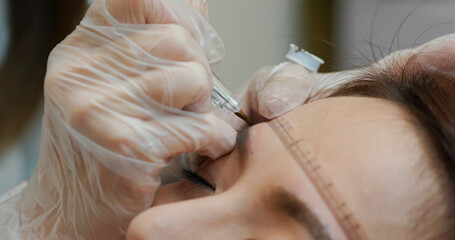Woman undergo micro pigmentation eyebrows in a beauty salon