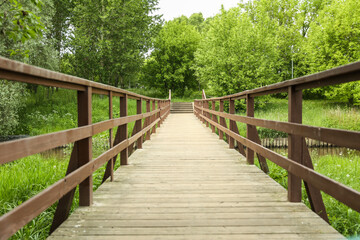 Naklejka na ściany i meble wooden bridge over a small river in summer