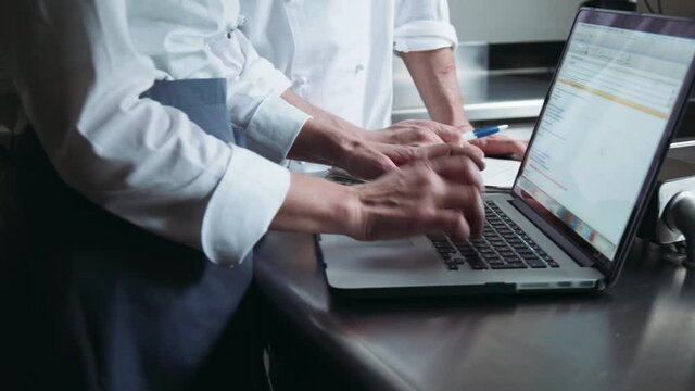 CU DS Chefs using laptop on kitchen counter / Florence, Tuscany, Italy
