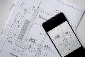 Flat lay of a construction plan with a black smartphone. Top view. Blank space to add text.