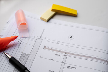 Closeup of a construction plan with a black pen and an orange highlighter.