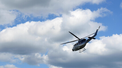 Fototapeta na wymiar Flying police helicopter airplane in blue sky with clouds.