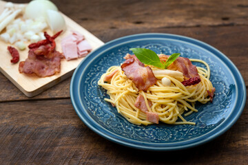 Fototapeta premium Stir-Fried Spaghetti With Dried Chili And Crispy Bacon on a bule plate a plate on dark woonen background