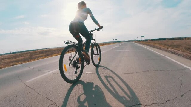 Woman ride a bike. Young woman riding a bicycle on the asphalt road at sunny day