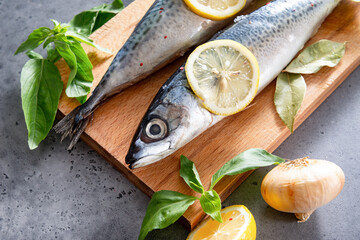  mackerel fish with spices and lemon slices on a cutting Board, Basil, onion on a gray background