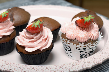 Chocolate cupcakes with strawberry cream. Decorated with half strawberries in chocolate. Next to the blanks and ingredients for cupcakes.