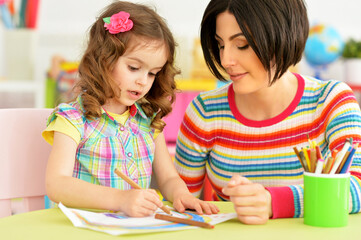 Close up portrait of little cute girl with mother drawing