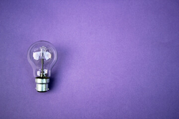 light bulb on purple background with purple copy space behind light bulb 